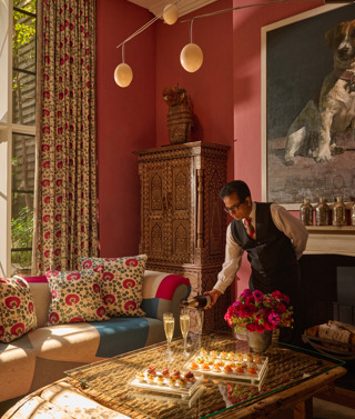 A waiter pouring a glass of Champagne in the Drawing Room at Crosby Street Hotel