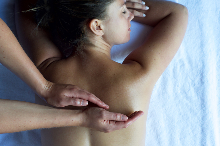 A woman lying on her front receiving a back massage