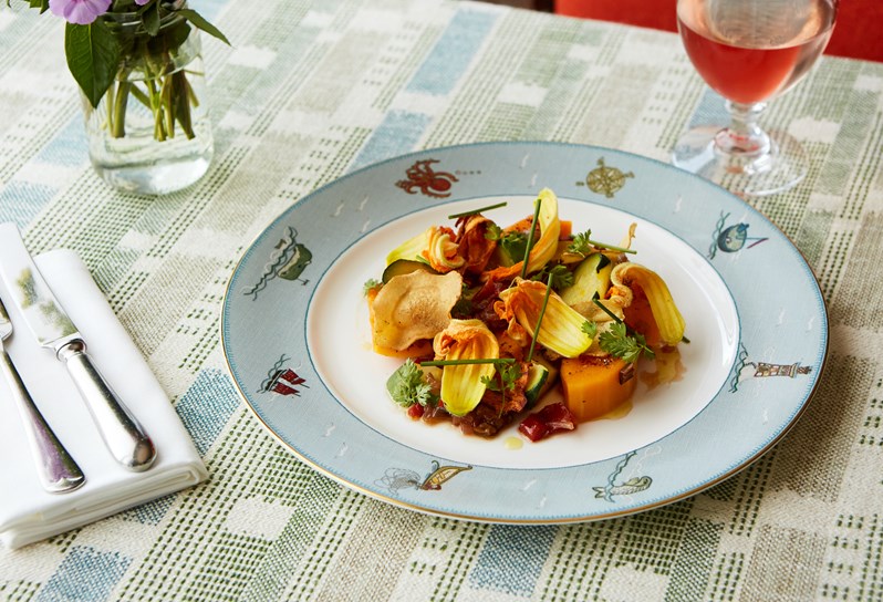 Squash and autumn vegetables salad on sailor's farewell crockery and a glass of rosé in the background