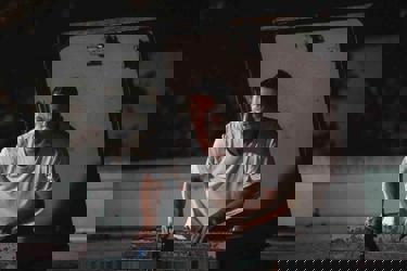 A still from the film 'Roofman'. A man in a tshirt can be seen slowly emerging from a escape hatch in a roof.