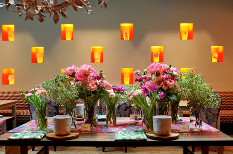 Shot of multiple arrangements of bright pink flowers sitting on a large table.