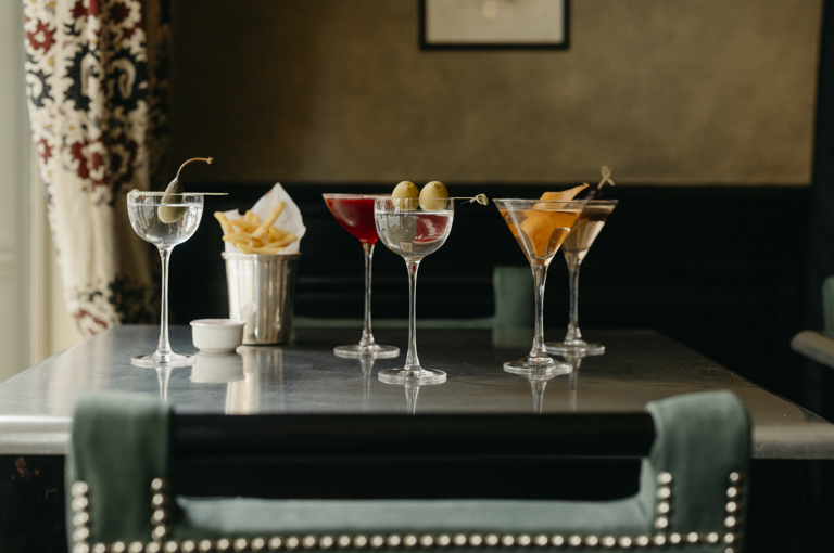 Wide shot of Martinis and bar snacks on a  table at Brasserie Max