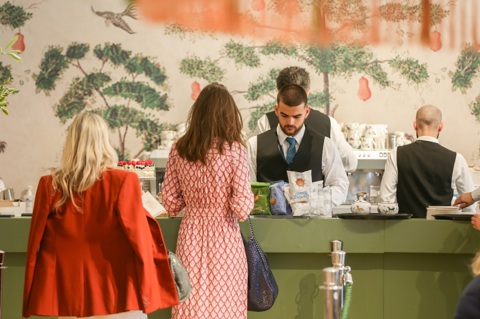 A shot of the bar at Refuel Cafe at Treasure House Fair. Two men are queuing for the bar and a man in waistcoat and tie is serving behind the bar