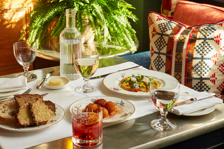 A wide shot of a table at Oscar with starters of bread, arancini and cured cod