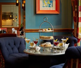 An image of the Afternoon Tea with a Twist at Oscar, Charlotte Street Hotel. The table displays the afternoon tea set up and cocktails.