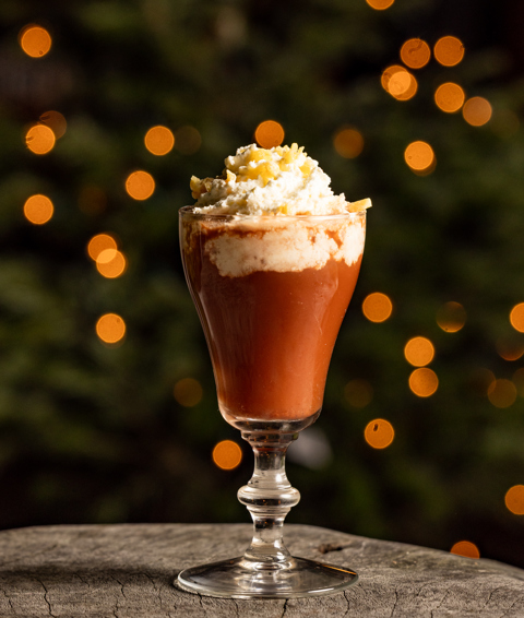 A cream-topped cocktail on a wooden surface