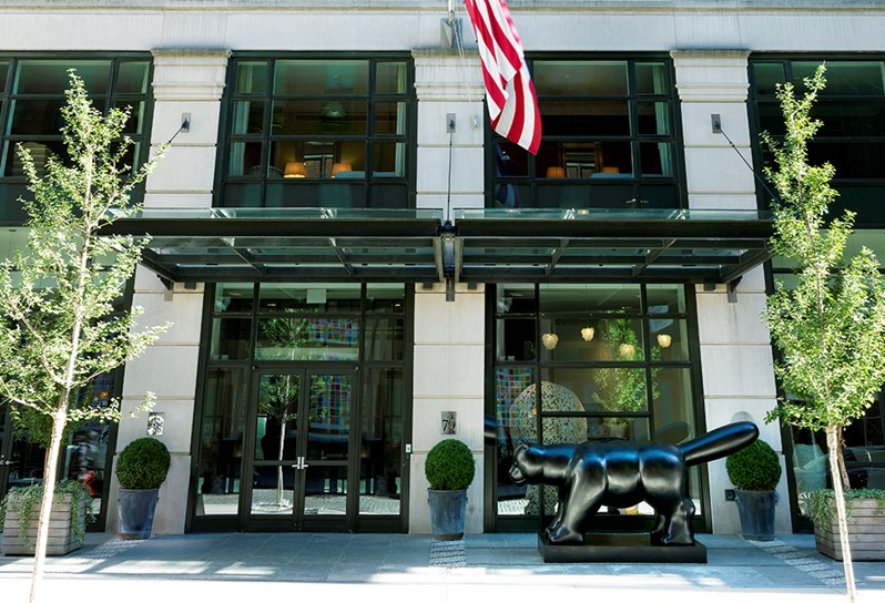 Exterior of Crosby Street Hotel with floor to ceiling windows and a large bronze cat by the Colombian artist Fernando Botero.