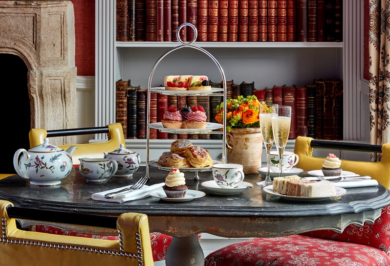 Champagne afternoon tea for two with sweet and savory treats, served in Kit Kemp's Wedgwood range Mythical Creatures, placed on a stone top table in the Library.