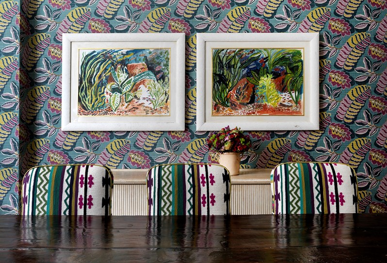 The Dora Carrington Room setup for a dinner. The far wall has a beautiful blue, lime green and pink wallpaper and there is a blue chandelier hanging above the table. At the end of the room there are doors that open onto Charlotte Street.