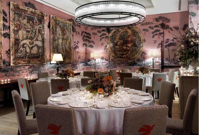 The Anrep private room with hand painted wallpaper by Melissa White, featuring Kit Kemp's mythical creatures, set up for private dining on round tables with stunning flower centerpieces.