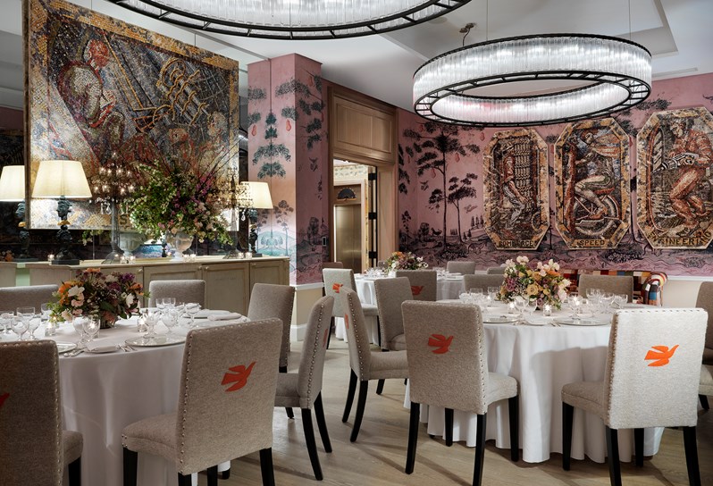 The Anrep private room with hand painted wallpaper by Melissa White, featuring Kit Kemp's mythical creatures, set up for private dining on round tables with stunning flower centerpieces and surrounded by mosaic artwork.