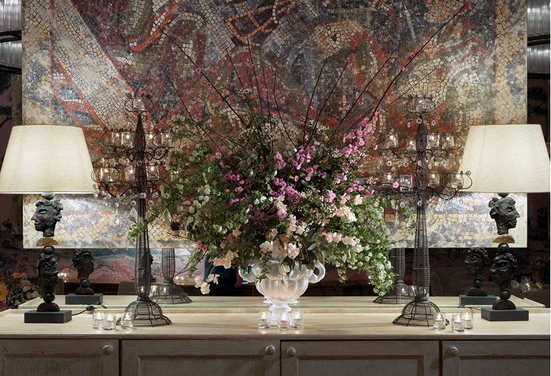 An original honesty bar cabinet in the Anrep private room with extraordinary original artwork around; a reproduction of Anrep mosaics from London's National Gallery, two eclectic designed lamps and a stunning fresh flower arrangement.