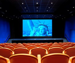 The state-of-the-art screening room with 130 comfortable leather seats in bright coral, projecting the Statue of Liberty on the advanced screen.