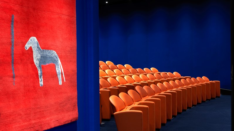 The entry to the state-of-the-art screening room with 130 comfortable leather seats in bright coral and electric blue walling.