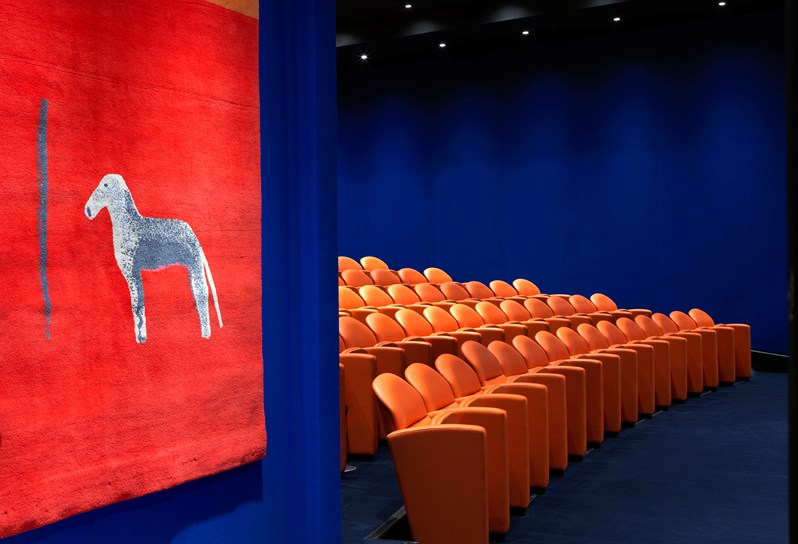 The entry to the state-of-the-art screening room with 130 comfortable leather seats in bright coral and electric blue walling.