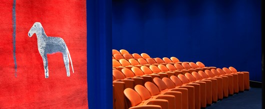 The entry to the state-of-the-art screening room with 130 comfortable leather seats in bright coral and electric blue walling.