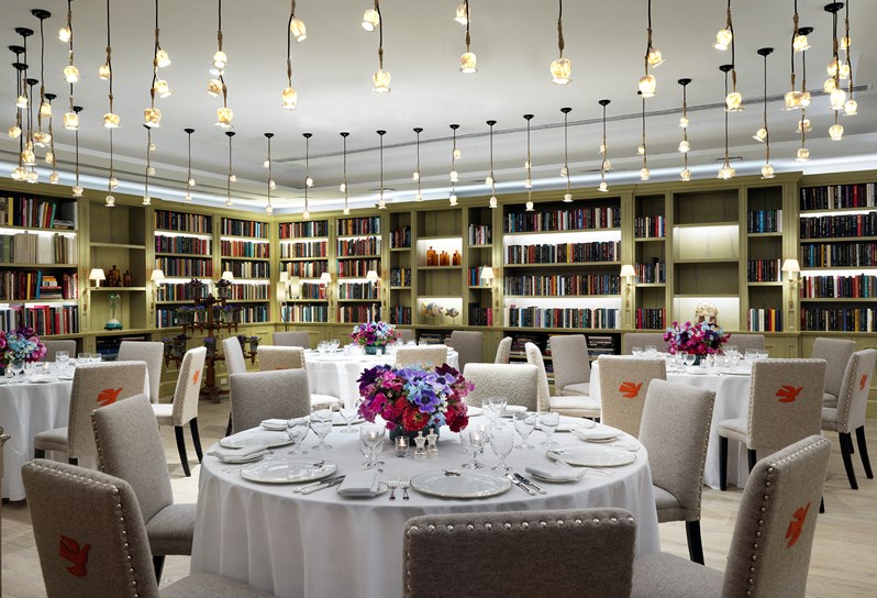 The book lined Reading Room set for a private dinner on round tables, complete with place settings in Kit Kemp's range for Wedgwood, Mythical Creatures, and beautiful flower arrangements.