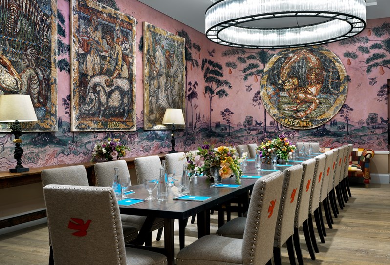 The Anrep private room with hand painted wallpaper by Melissa White, featuring Kit Kemp's mythical creatures, and mosaic artwork, set up in boardroom meeting style with comfortable chairs.