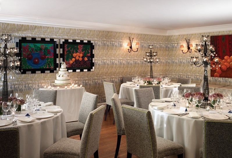 A private room setup for a wedding breakfast on round tables with candelabra and flowers to decorate.