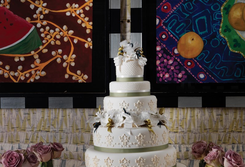A wedding cake with flowers and candles surrounding it.