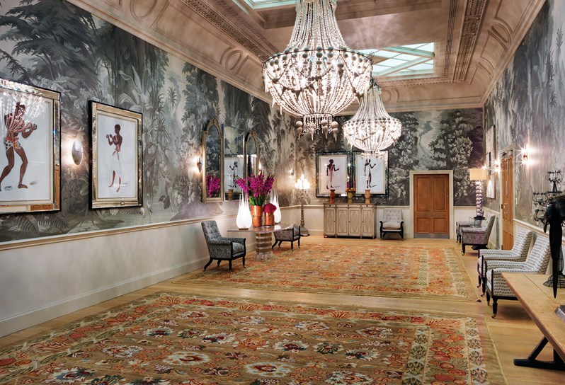Shooting Gallery private room furnished with an eclectic collection of furniture and comfortable armchairs. The walls are covered in original artwork by Oliver Messel.