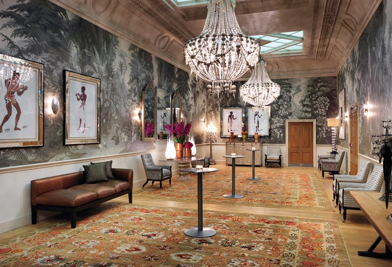 Shooting Gallery set with high top tables with beautiful original artwork and a dramatic wallpaper featuring jungle landscapes in grey sepia tones.