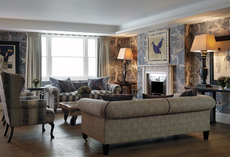 Nash event room has colourful walls with a beautiful sofas and arm chairs, fresh flowers and two eclectic designed lamps.