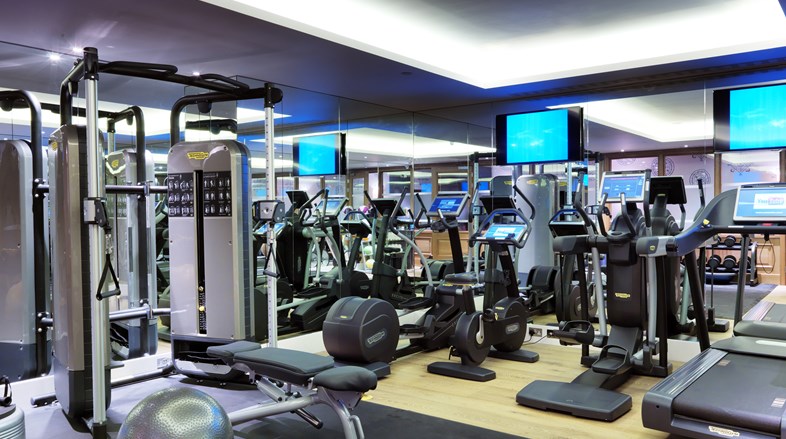 The gym containing cross-trainers, treadmills, bicycles, free weights and pilates ball, with padded mats on the floor and floor to ceiling mirrors on two walls as well as TV screens.