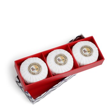 A box of three round soaps scented in lavender eucalyptus and wrapped in white paper. They are presented in an elongated red box with a lid featuring a blue rick rack design.