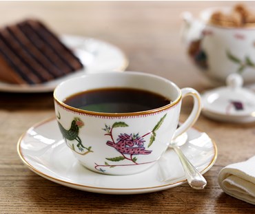 Kit Kemp for Wedgwood. Mythical Creatures cup and saucer filled with coffee. The design features a series of characters and patterns that have a primitive, folkloric feel