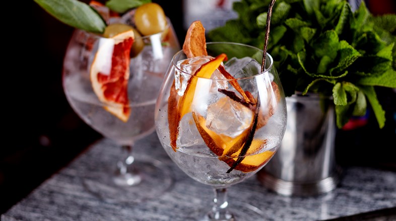 Gin cocktails in balloon glasses garnished with fresh peaches