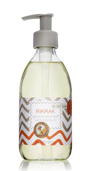 A 295ml glass bottle of bath and body oil with pump dispenser scented with Gardenia Greenleaf. Label has an orange and grey rick rack design applied.