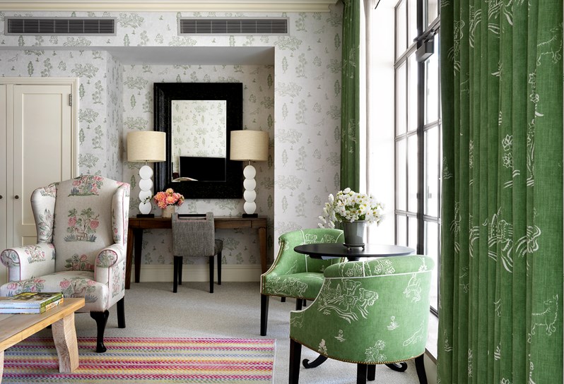 A spacious terrace of a Terrace Suite, including a dining area with table and chairs for four, as well as a lounge area with a comfortable sofa and coffee table. Terrace boasting leafy plants, colorful details and sweeping views of Manhattan.