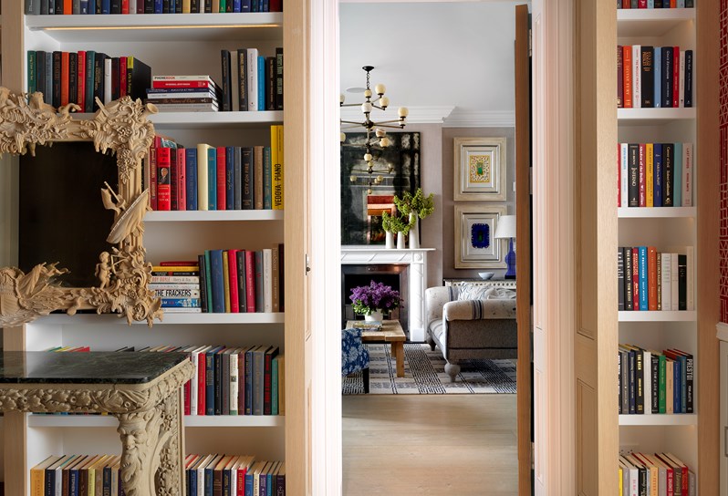 Doorway looking in to the living room of The Whitby Suite, with floor to ceiling book shelves filled with books in an array of colors on both sides of the door frame.