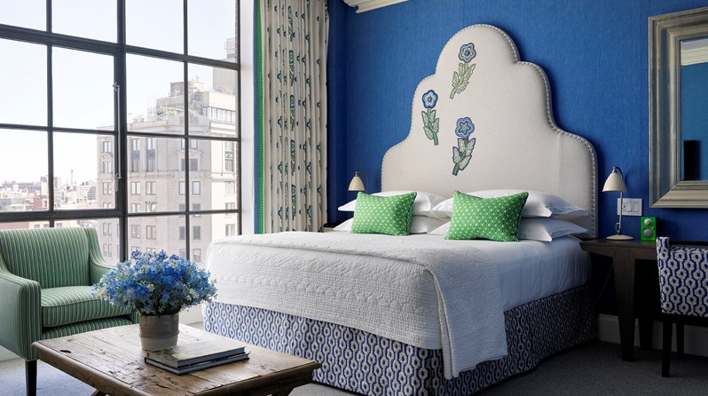 A spacious bedroom in this beautiful junior suite with high ceilings, floor to ceiling windows and views over SoHo. A beautiful colour scheme with bright blue walls and a cream embroidered headboard.