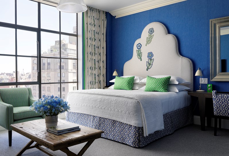 A spacious bedroom in this beautiful junior suite with high ceilings, floor to ceiling windows and views over SoHo. A beautiful colour scheme with bright blue walls and a cream embroidered headboard.