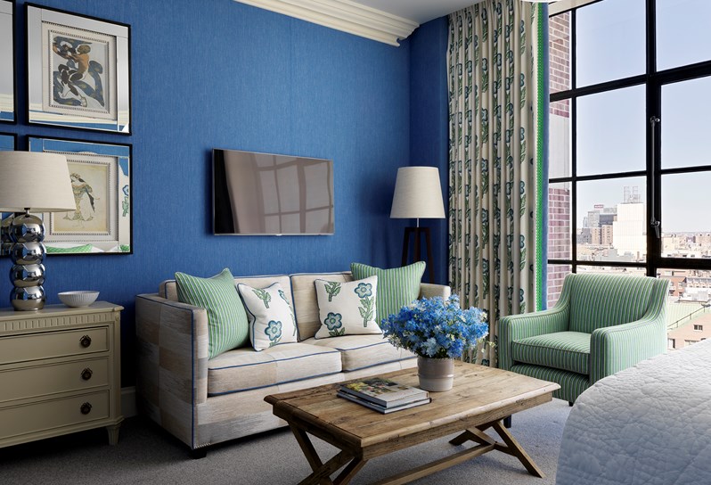 A spacious sitting area in this junior suite with high ceilings, floor to ceiling windows and views over SoHo. A beautiful colour scheme with bright blue walls and colourful details.