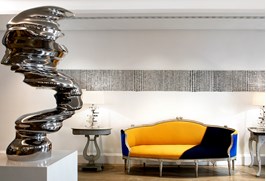 Haymarket Hotel reception area featuring a sculpture by Tony Cragg in the foreground, with a graphic orange sofa set against the wall in the background.