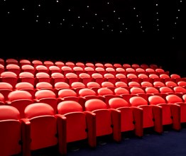 The screening room at Soho Hotel. Rows of red cinema style chairs face towards a screen.