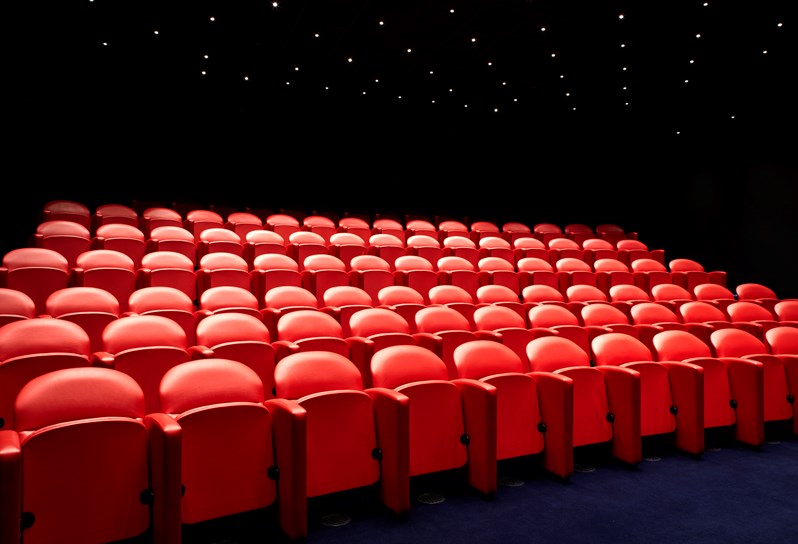 The screening room at Soho Hotel. Rows of red cinema style chairs face towards a screen.
