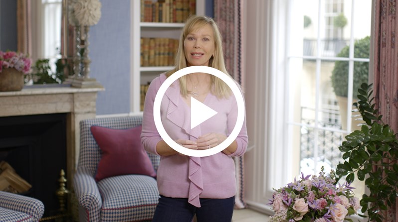 Kit Kemp, Creative Director of Firmdale Hotels, standing in the Townhouse at Haymarket Hotel. Overlaid on the image is a play button icon.