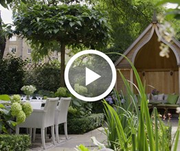 The luscious garden at Number Sixteen  Hotel with a focal wooden pergola at the end of the garden. Overlaid on the image is a play button icon.