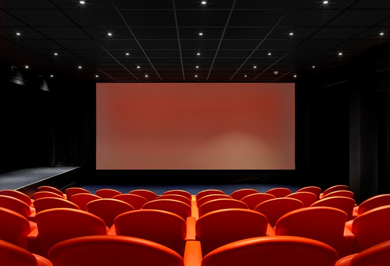 The Screening Room at Charlotte Street Hotel. Rows of red cinema style seats face towards the cinema screen.