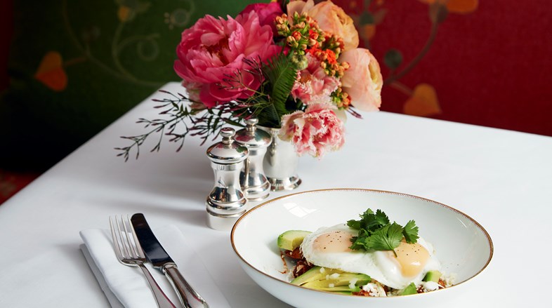 Two poached eggs on a bed of vegetables and avocado.