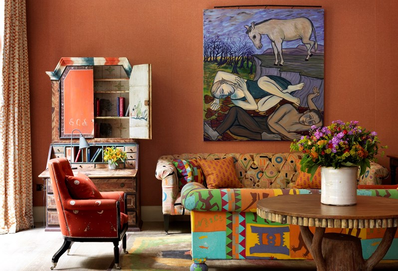 The Drawing Room at Ham Yard Hotel with burnt orange walls and vibrantly upholstered sofas.