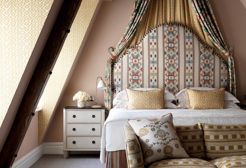The Junior Loft Suite at Covent Garden Hotel decorated in pale pink tones with a pastel floral fabric half tester over the bed