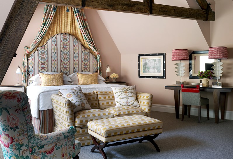The Junior Loft Suite at Covent Garden Hotel decorated in pale pink tones with a pastel floral fabric half tester over the bed