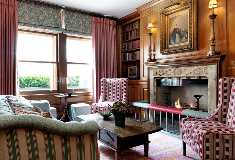 The wood panelled library with open fireplace and red arm chairs