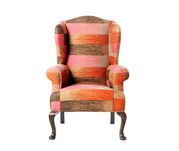 Front facing Kit's Wing Armchair, upholstered in Kit Kemp for Christopher Farr 'Ikat Weave' fabric in Orange, with off white piping; legs in 'Haymarket Grey' timber finish, with chrome studding at the top of the leg