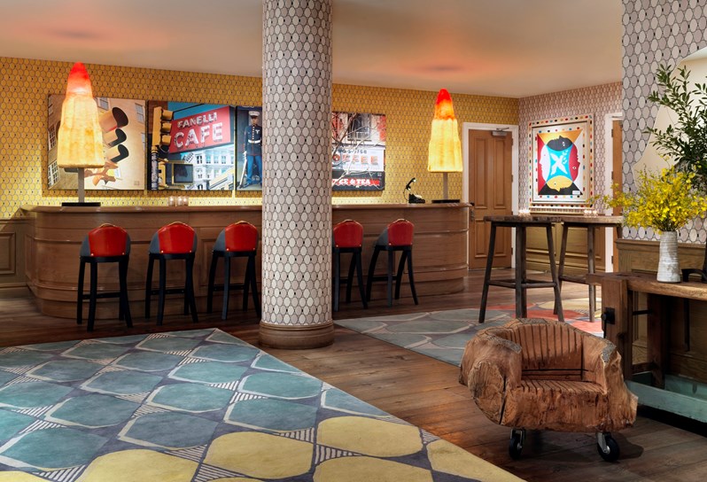 The vibrant Events Lobby at Crosby Street Hotel with yellow walls and colorful mosaic columns